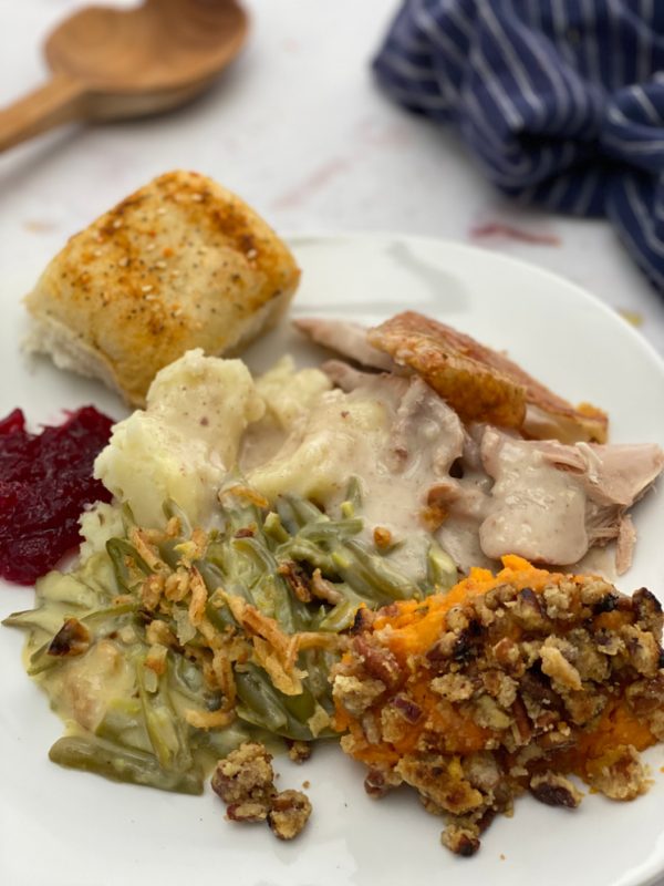 Plat of thanksgiving dinner with roll turkey green bean casserole sweet potatoes  turkey cranberry sauce