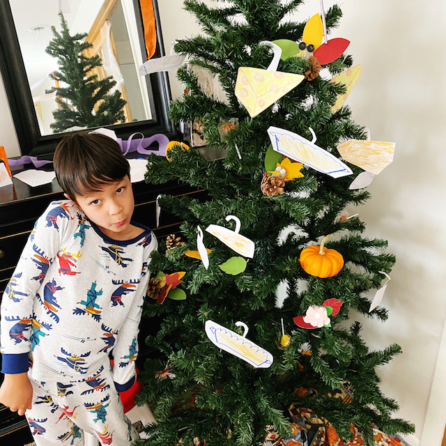 Thanksgiving tree and boy standing by it after decorating.