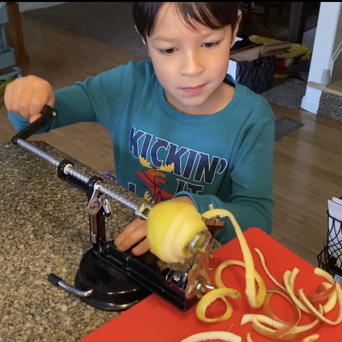 boy using an apple peeler corer slicer