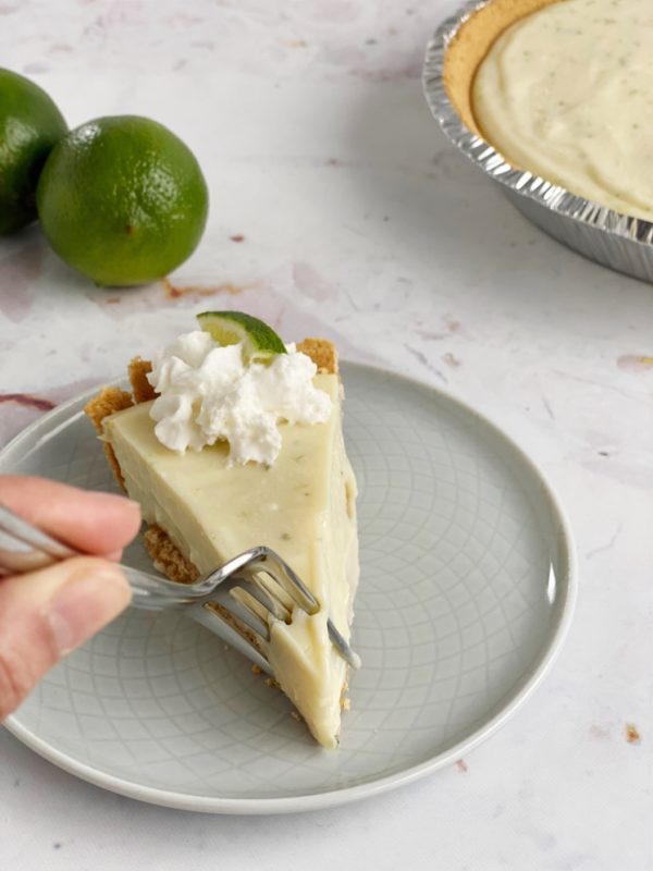 fork in slice of key lime pie with limes