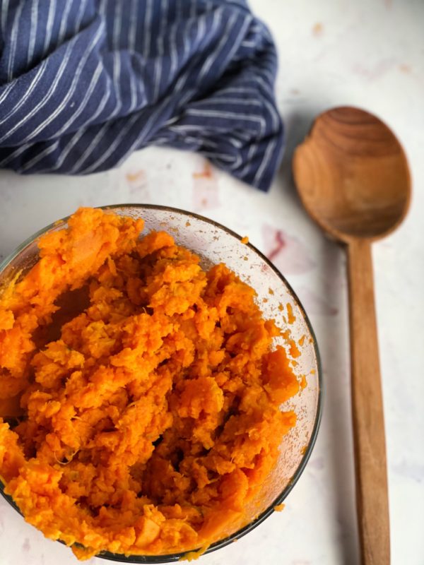 Mashed sweet potato in bowl with spoon