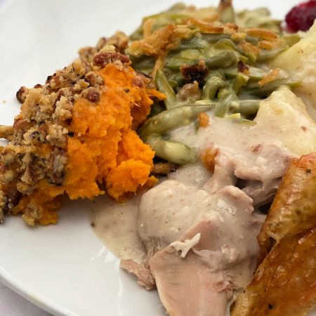 Plate of thanksgiving dinner food. sweet potatoes green beans turkey and mashed potatoes