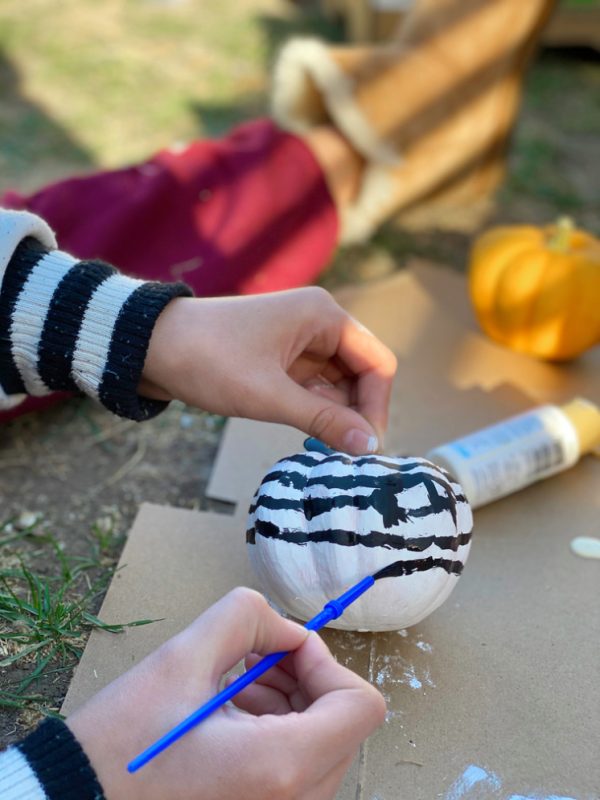 hands painting black and white pumpkin