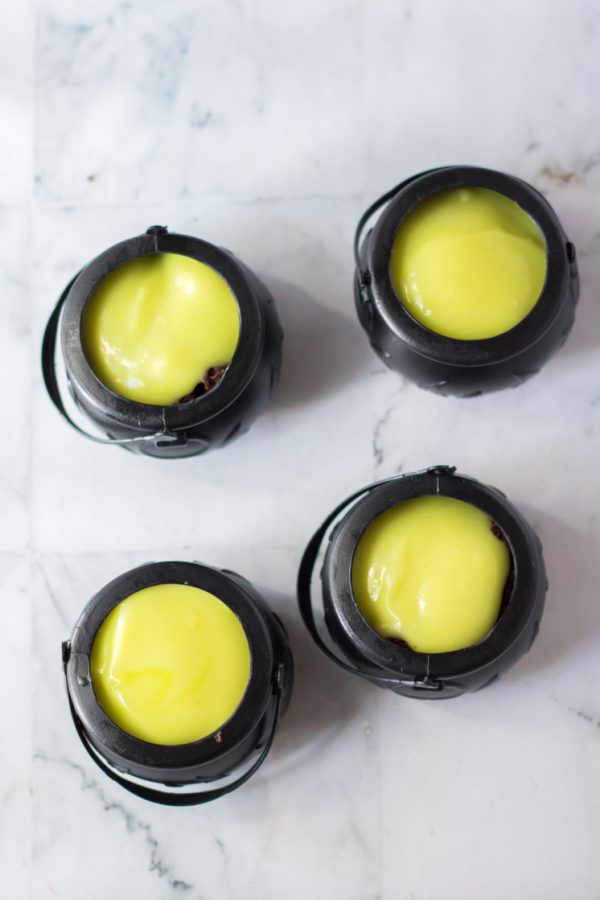 Mini Cauldron cupcakes topped with green pudding