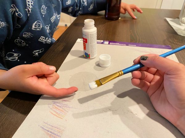 child hand with paint on paint brush
