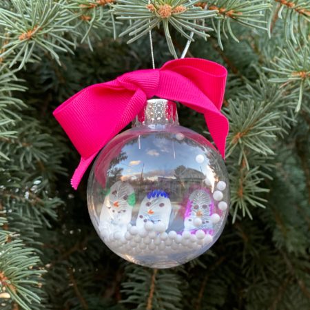 pink bow on snow globe ornament with snowmen