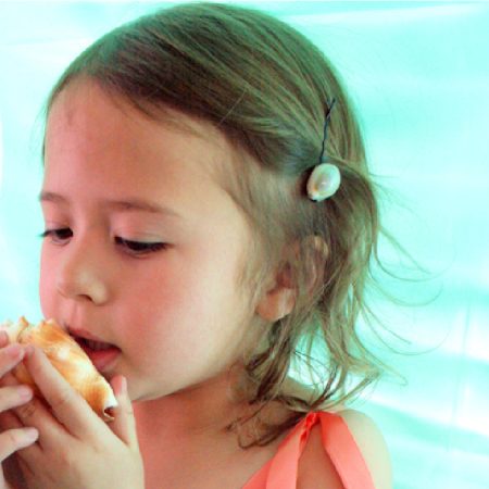 Little girl with shell hair clip holding shell